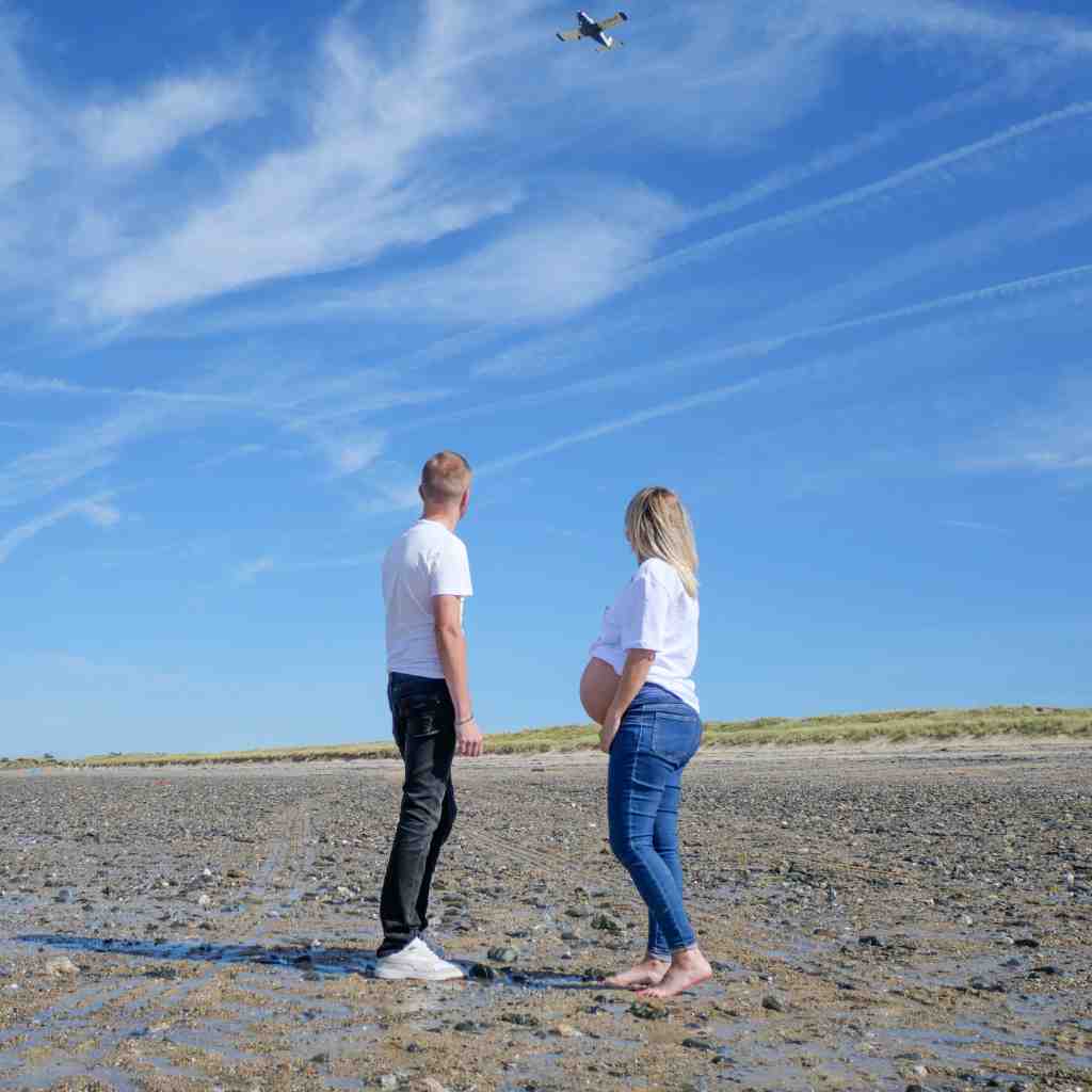 Séance grossesse vidéo sur la plage dans la Manche, couple marchant ensemble, créant des souvenirs inoubliables.