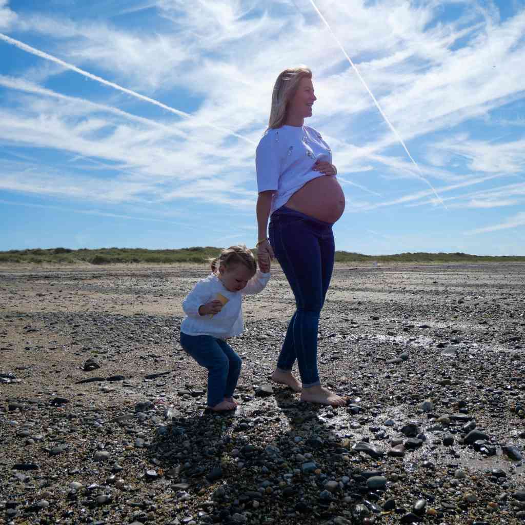 Vidéaste capturant une séance grossesse en vidéo sur la plage de la Manche, équipements professionnels pour des images de qualité.