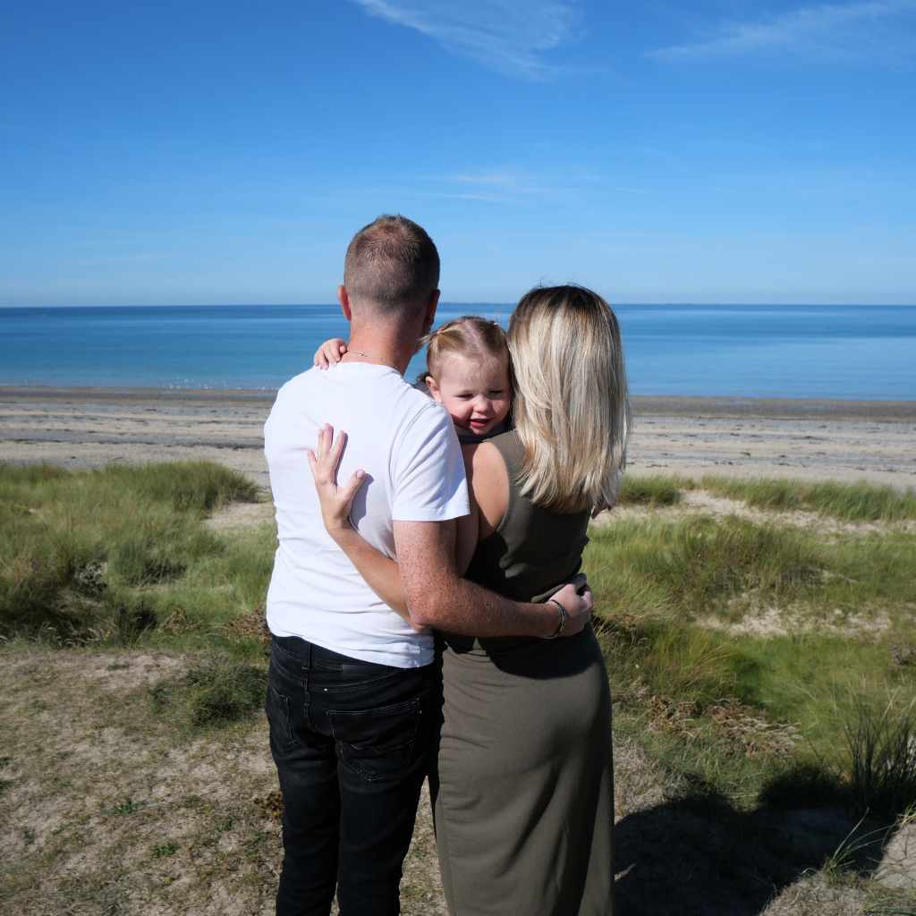 Parents et enfant jouant sur le sable, ventre rond visible